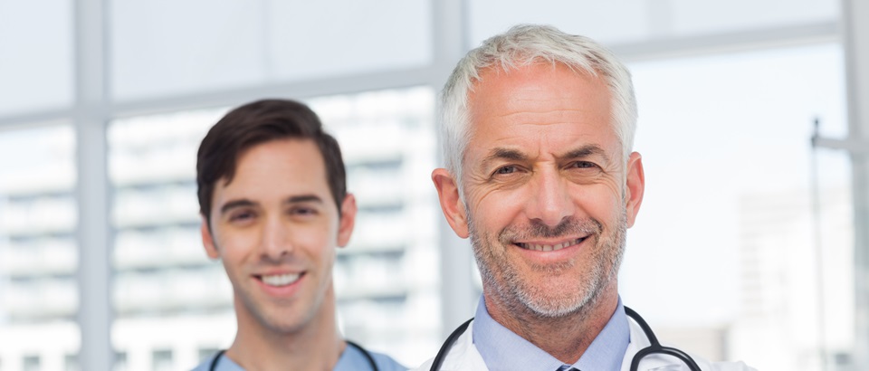 50s, Mature Adult, Man, Male, Caucasian, 20s, Young Adult, Indoors, Looking At Camera, Doctor, Practitioner, Profession, Professional, Specialist, Lab Coat, Stethoscope, Confident, Nurse, Scrubs, Blue, Standing, Clinic, Healthcare, Hospital, Medical, Staff, Attractive, Handsome, Grey Hair, Portrait, Team, Smiling, Happy, Cheerful, Friendly